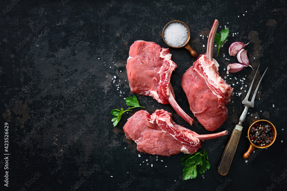 Raw French Rack Raw veal Frenched Racks meat with ingredients on rustic dark background ...