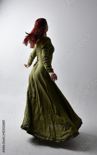Canvas Print full length portrait of red haired girl wearing celtic, green medieval gown  with shadowy backlighting