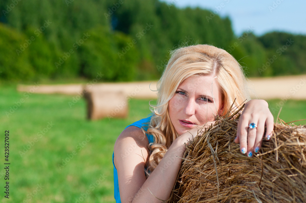 woman in blue dress sleeping on a bale of hay woman in blue dress sleeping on a bale of hay