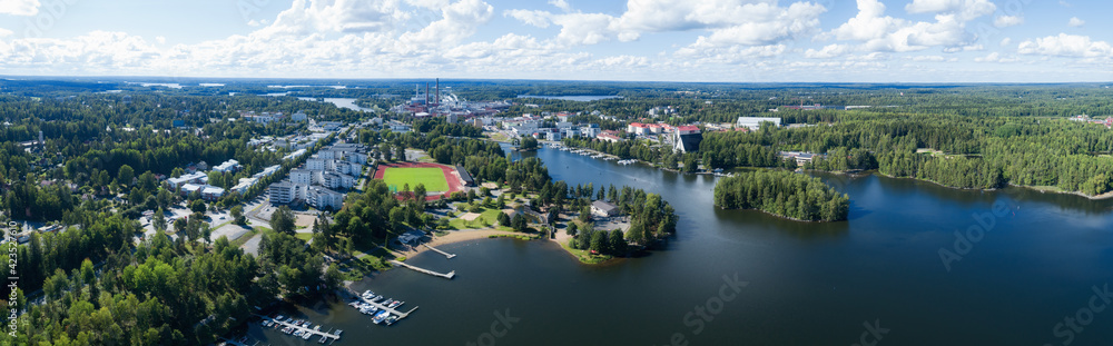 Beautiful view of Valkeakoski city at sunny summer day with blue sky and clouds. Aerial view of blue lake with bridge and green summer town in Finland.