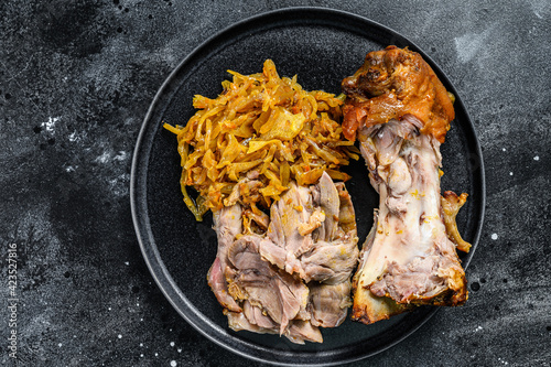 Baked Pork knuckle with braised cabbage. Black background. Top view