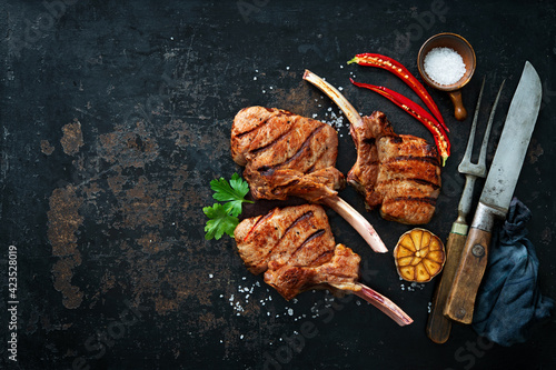 Grilled veal meat ribs cutlets with ingredients on rustic dark background photo