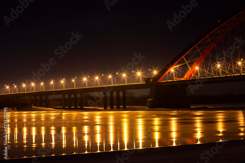 night view of the bridge over the river, the lanterns of which brightly illuminate everything around 