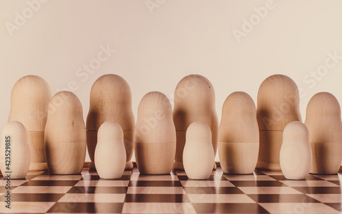 Two rows of impersonal nesting dolls on a chessboard. Conceptual image.