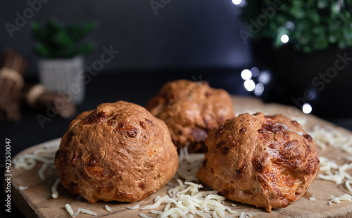 Crunchy crust of tasty home baked flax flour bagels, mozzarella cheese, wooden board, cloth, selective focus, dark background. Natural light, fairy lights