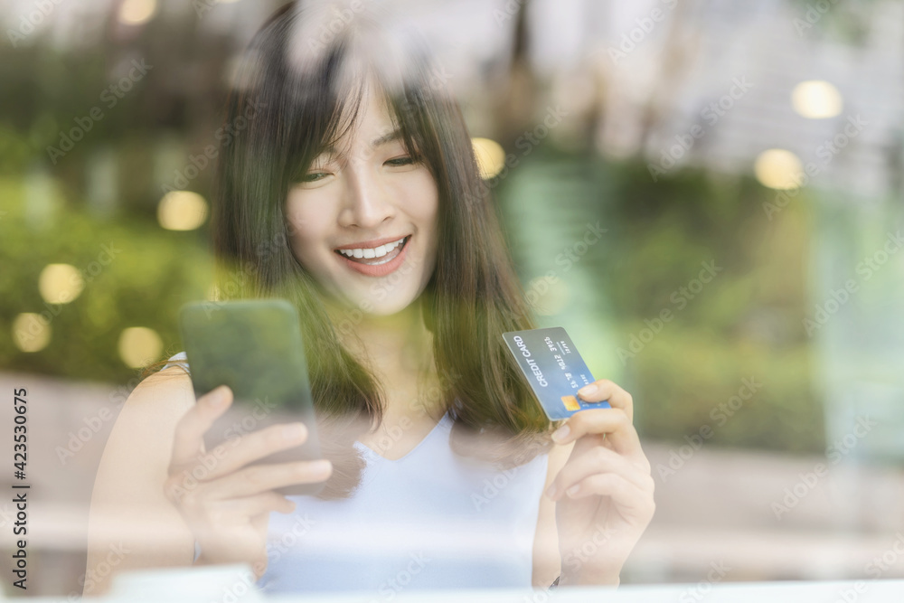 Asian woman using credit card with mobile phone for online shopping in modern coffee shop, technology money wallet and online payment concept, credit card mockup Asian woman using credit card with mobile phone for online shopping in modern coffee shop, technology money wallet and online payment concept, credit card mockup