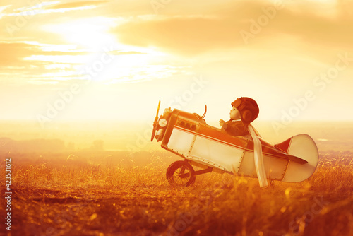 Schilderij op canvas A small child plays with a toy plane, imagines himself as an aviator and dreams of flying