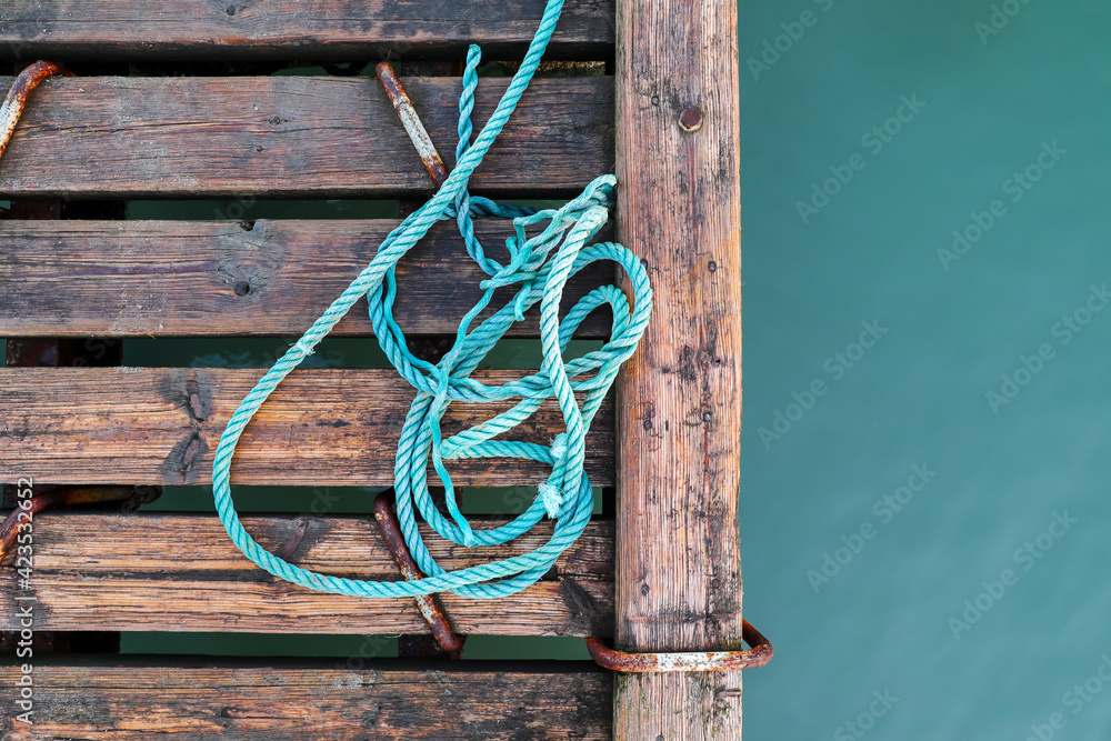 Fototapeta premium Wooden pier with blue sea. Wood floor or terrace beside the blue crystal clear water and a rope.