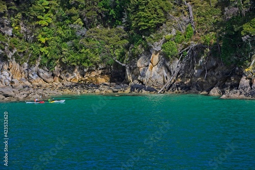 Wide vista of sea canoe rock outcrop with trees and green sea.