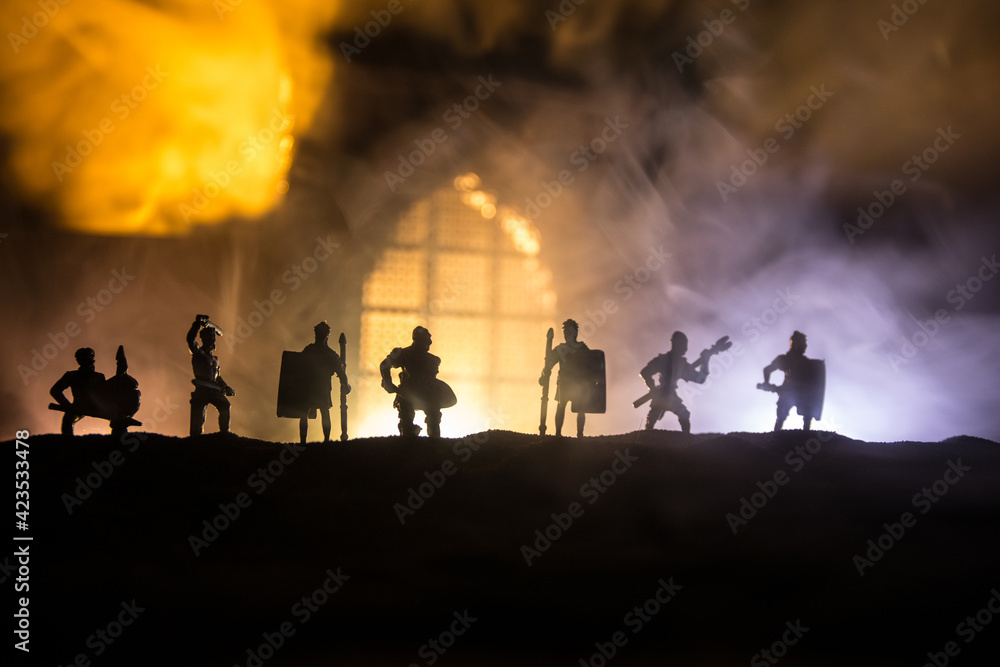 Medieval battle scene with cavalry and infantry. Silhouettes of figures as separate objects, fight between warriors on sunset foggy background.