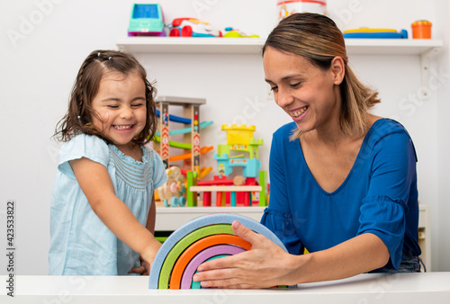 Two-year-old girl and her young kindergarten teacher, playing and learning in kindergarten.