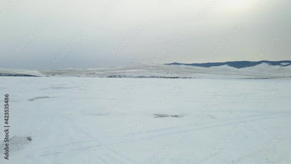 Baikal Lake Landscape with Cracked Frozen Ice Surface Covered with Snow in Winter. Aerial View Baikal Lake Landscape with Cracked Frozen Ice Surface Covered with Snow in Winter. Aerial View