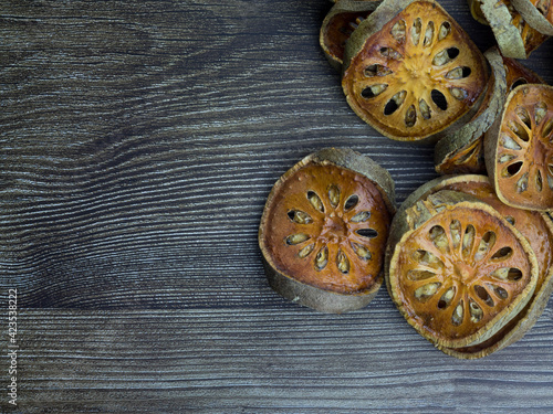 The bael fruit is turned and then dried, blown away on a wood grain background.