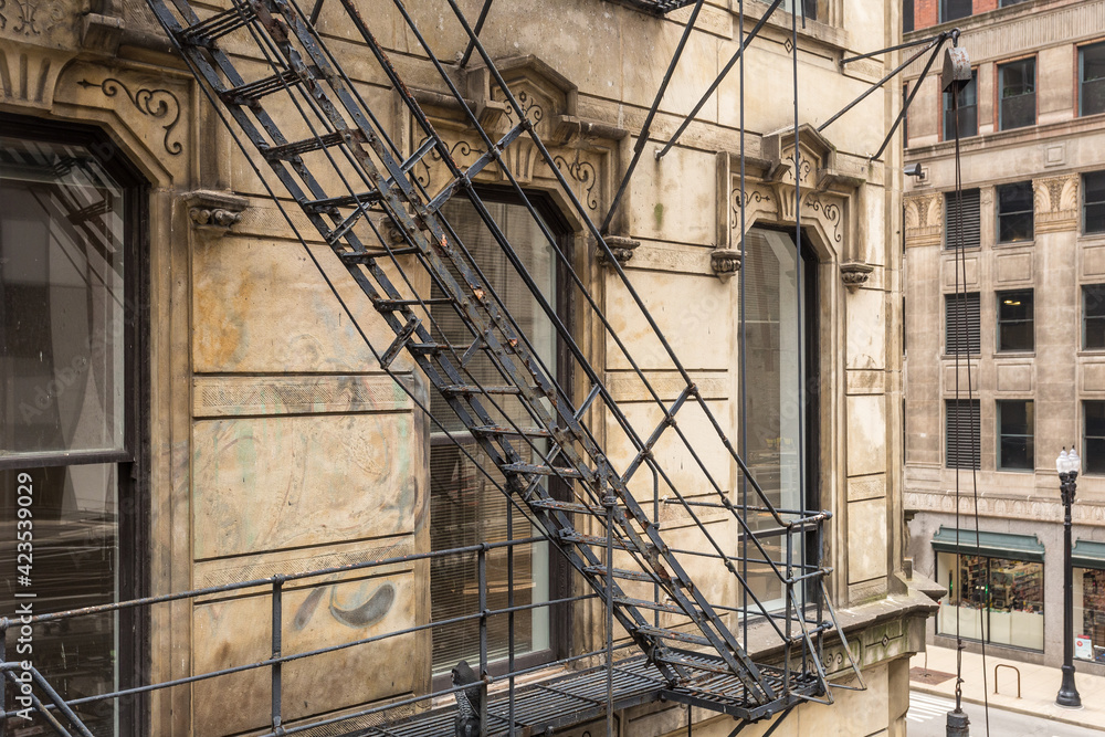 Obraz premium Side of vintage art deco building with steel fire escape in urban Chicago on overcast day