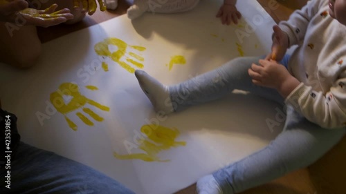 Family makes handprints with colored paint on paper 

