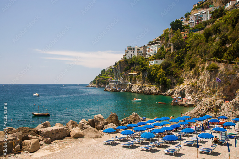 Beach at Amalfi Italy with umbrellas up and sea and hills in the background
