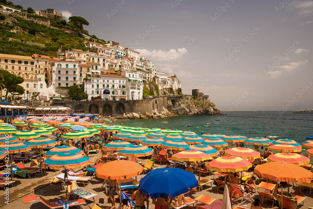 Beach at Amalfi Italy with umbrellas up and sea in background.