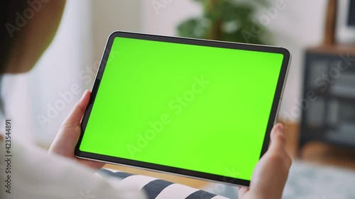 Close up of woman holding in hands a digital tablet with green screen for internet online, chroma key screen for advertising.