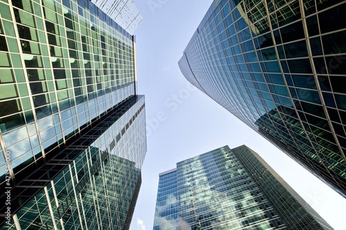 Bottom up view of modern office buildings in the city's business district. Glass facades of skyscrapers with contrasting highlights and reflections. Economy development, finance and business concept. 