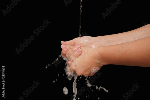 Woman use soap and washing hands on black background. Hygiene concept hand detail. Closeup of person washing hands isolated.