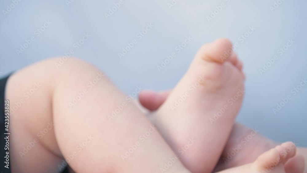 Happy family. Mother's hands hold the baby's legs. The legs of a newborn baby are caressed by a mother. Happy family. Mother's hands hold the baby's legs. The legs of a newborn baby are caressed by a mother.