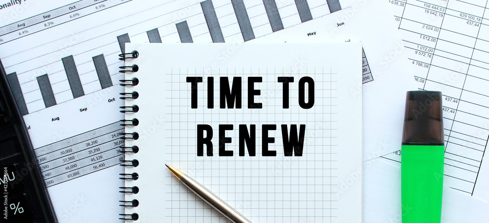 Text TIME TO RENEW on the page of a notepad lying on financial charts on the office desk. Text TIME TO RENEW on the page of a notepad lying on financial charts on the office desk.