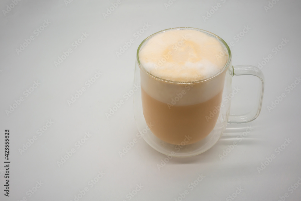 Hot Thai milk tea with milky foam sprinkle with cocoa power for decoration in double wall glass isolated on white Hot Thai milk tea with milky foam sprinkle with cocoa power for decoration in double wall glass isolated on white