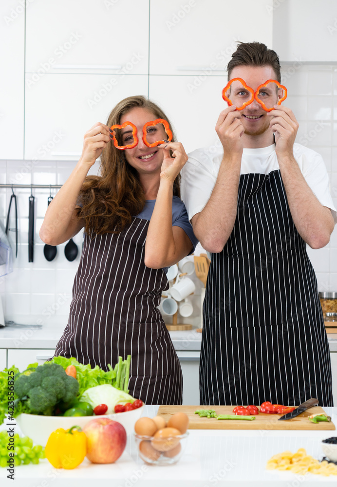 young caucasian couple holding fruit in hand and standing in kitchen to prepare breakfast young caucasian couple holding fruit in hand and standing in kitchen to prepare breakfast