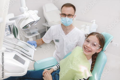 Top view shot of a dentist at his young patient in dental chair