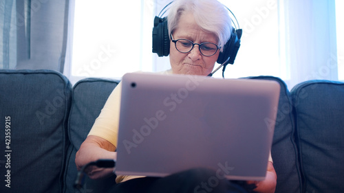 Elderly woman with headset having video call with family and waving to camera. Old people and technology. High quality photo photo