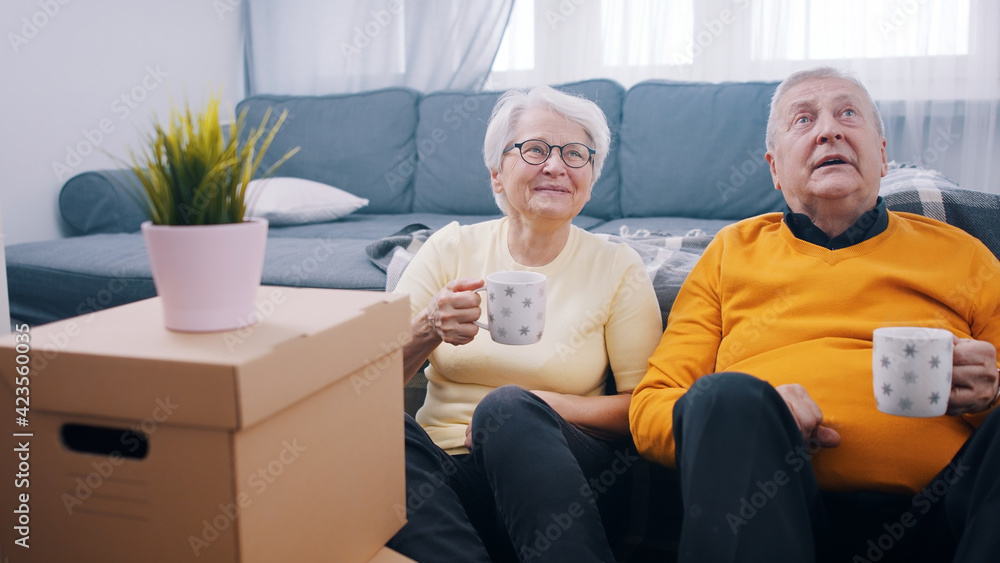 Happy retired couple relocating to new appartment. Drinking coffee surounded by cardboard boxes. buying new property. High quality photo