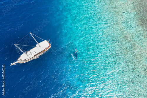 White sailboat, yacht in shallow tropical water. People snorkeling with whale shark. Amazing nature view, aerial seascape. Summer recreational vacation, water sport activity. Blue ocean coral sea reef © icemanphotos