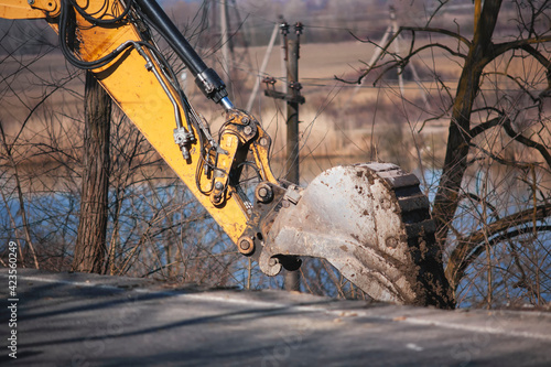 repair of an asphalt road after a flood. old excavator bucket. excavator makes road repairs