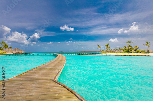 Maldives island, luxury water villas resort and wooden pier jetty. Beautiful sky and clouds and beach background for summer vacation holiday and travel concept. Tourism adventure destination seaside