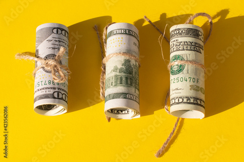 Twisted bundle 100 dollar bills on a yellow background