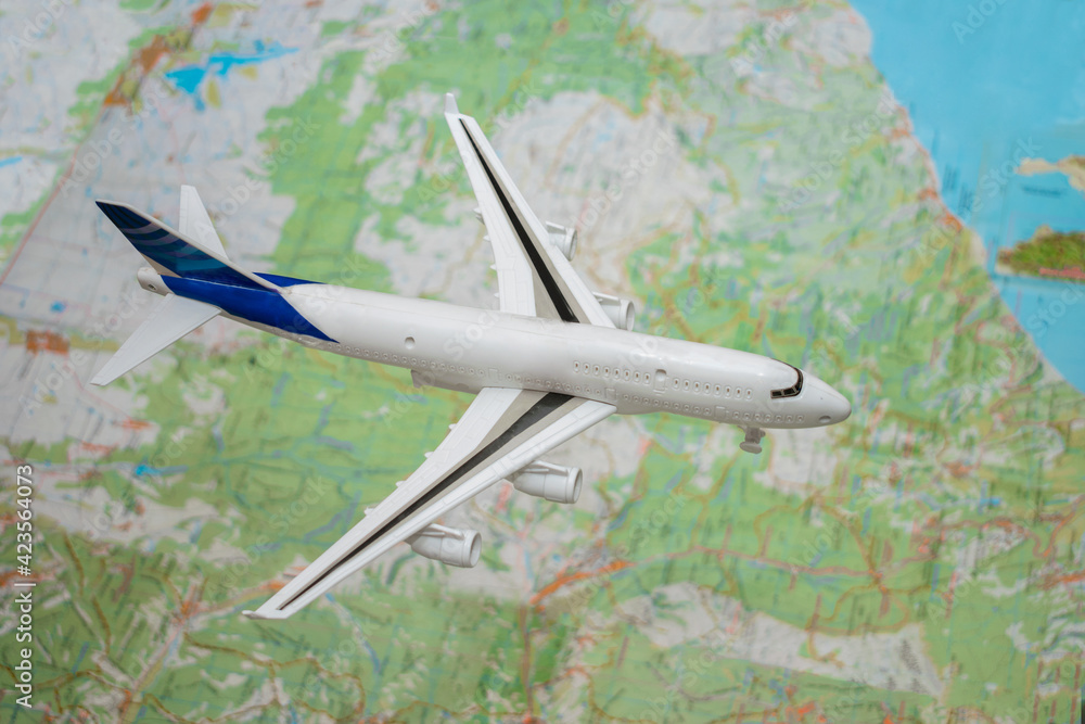 Obraz premium A toy plane flies over the geographic map of the world. Airplane travel concept