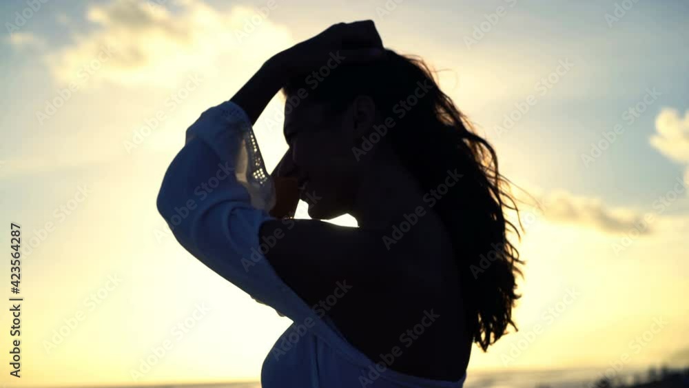 Silhouette of happy young woman enjoying sunset on the beach Silhouette of happy young woman enjoying sunset on the beach