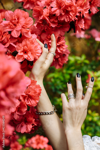 hands with rings of a girl in azalea flowers