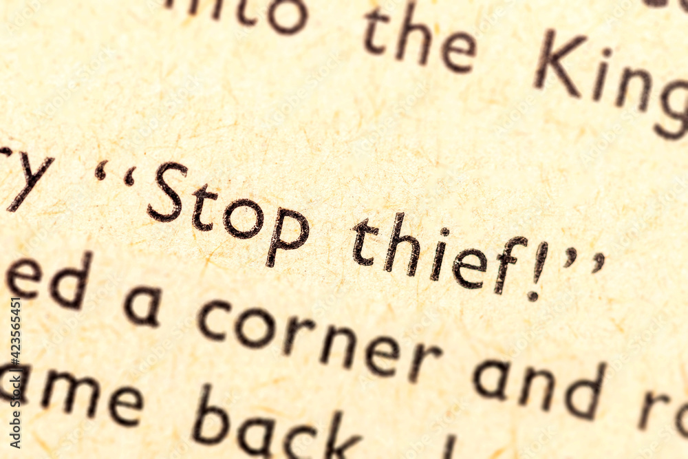 Stop thief! Single text line focus, words in an old book dramatic macro extreme closeup Literature thievery, burglary, robbery, stealing and crime Thief symbol, abstract language quote concept, nobody