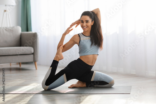 Flexible young lady practicing yoga while staying home