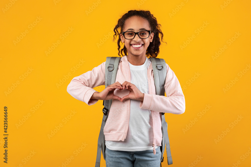 Cheerful beautiful girl making heart by hands at studio Cheerful beautiful girl making heart by hands at studio
