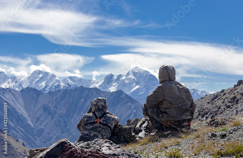 Two men in camouflage suits are conducting surveillance at the top of the mountain. © okyela