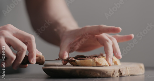 Man spreading chocolate hazelnut spread on baguette slices