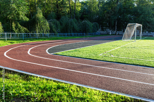 Small sports stadium with soccer field and running tracks. Summer, day, sunshine. © larison