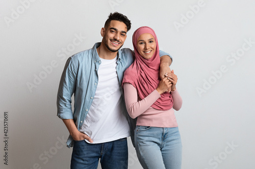 Happy Arabic Couple Man And Woman In Hijab Posing Over Grey Background