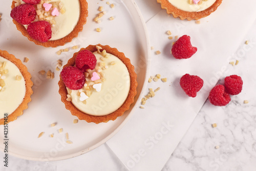 Billede på lærred Top view of small tartlet pastries with white cream, topped with raspberry fruit
