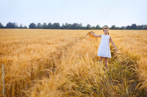 A little girl in a white dress runs through a wheat field.