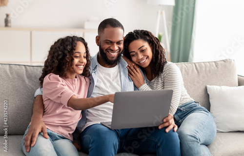 Happy african american family using laptop in living room © Prostock-studio