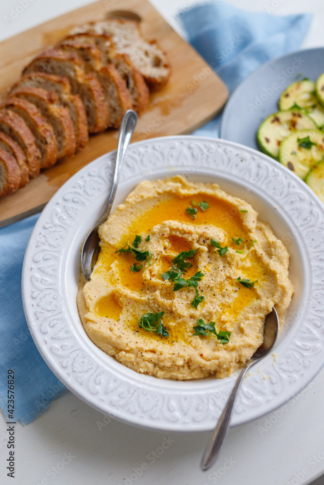 Top view of a plate of healthy homemade creamy hummus on a gray background zucchini and fresh bread for lunch Top view of a plate of healthy homemade creamy hummus on a gray background zucchini and fresh bread for lunch