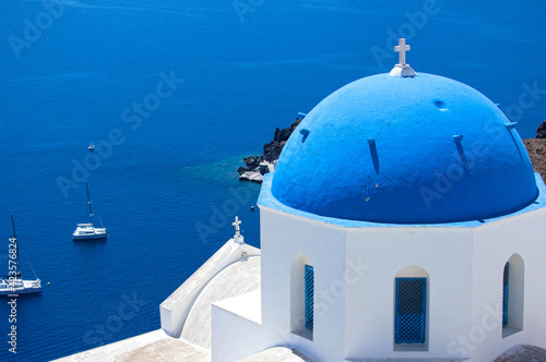 Oia town in Santorini, Greece. Blue domed churches Agios Spyridonas and Anastaseos.